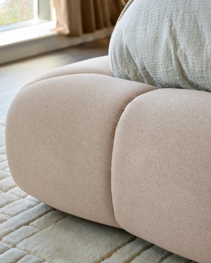 Close-up of a modular sofa in a neutral colour, with a textured rug and a pale green cushion.