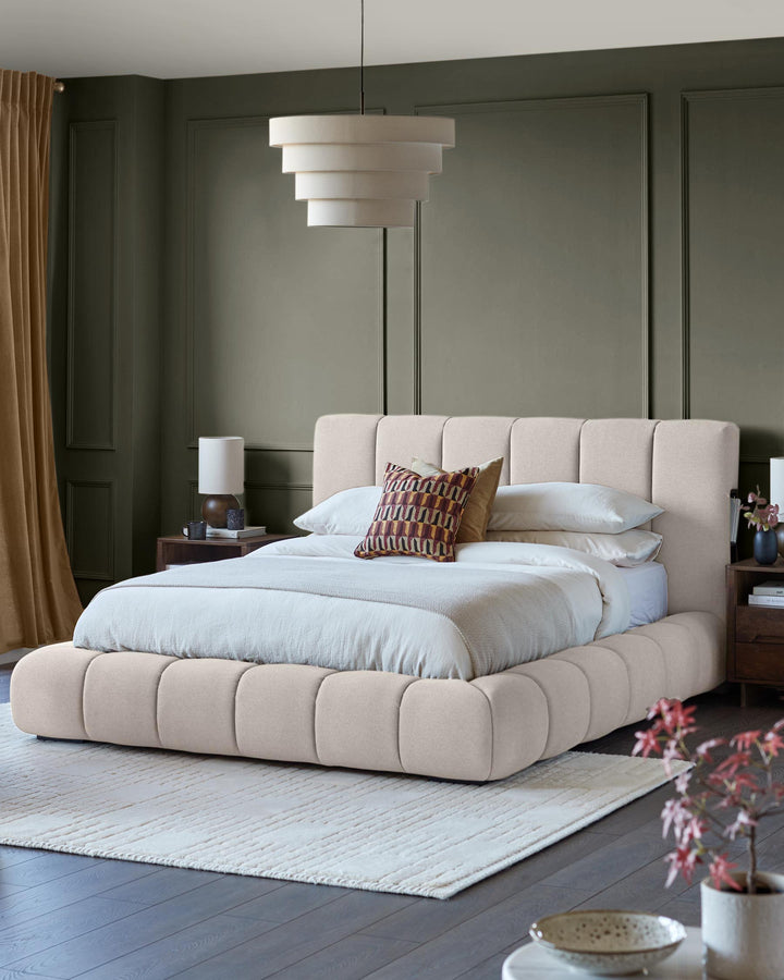 A bedroom featuring a modern, neutral-toned bed with a padded headboard and matching base, complemented by warm lighting.