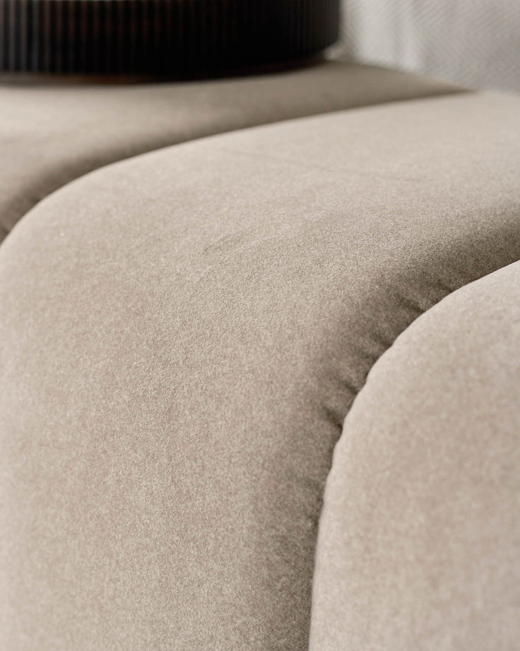 Lillian Bench in cream fabric, close-up detail of curved seating surface and upholstered texture.