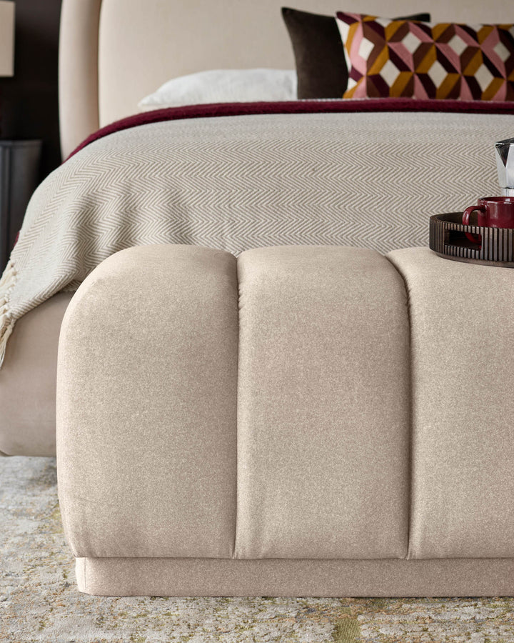 Cream fabric bench with quilted curved panels, positioned at foot of bed in bedroom setting.