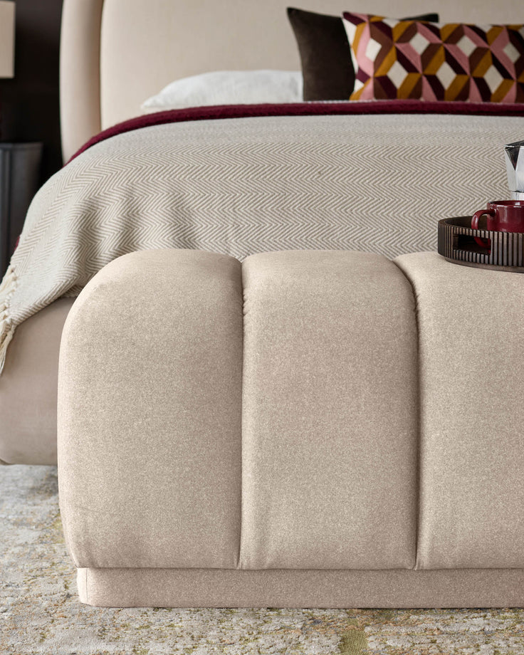 Cream fabric bench with quilted curved panels, positioned at foot of bed in bedroom setting.