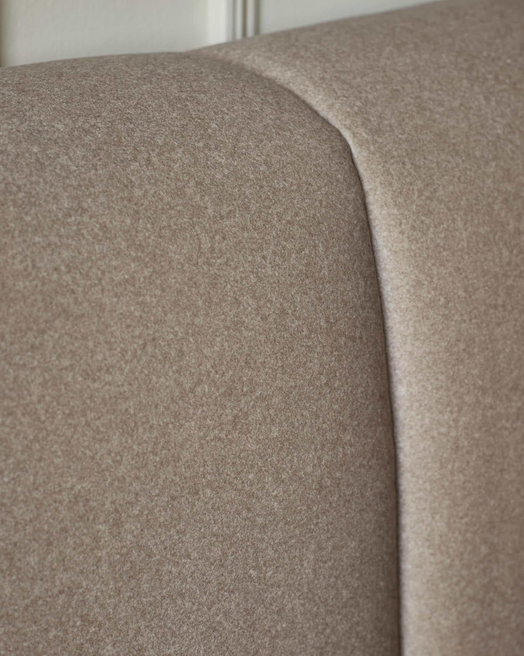 Lillian double ottoman bed in mocha fabric, close-up detail of curved headboard and seaming.