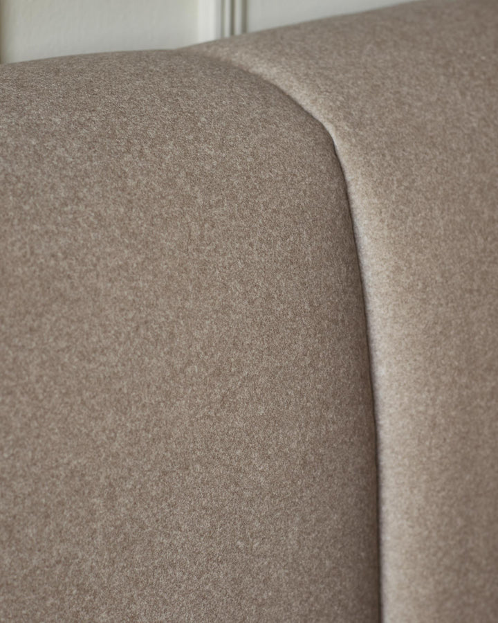 Close up of a beige, fabric headboard. Soft and textured, it's perfect for a comfy night's sleep.