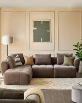 A stylish, modular sofa sits atop a patterned rug, complemented by tasteful cushions and a modern floor lamp.