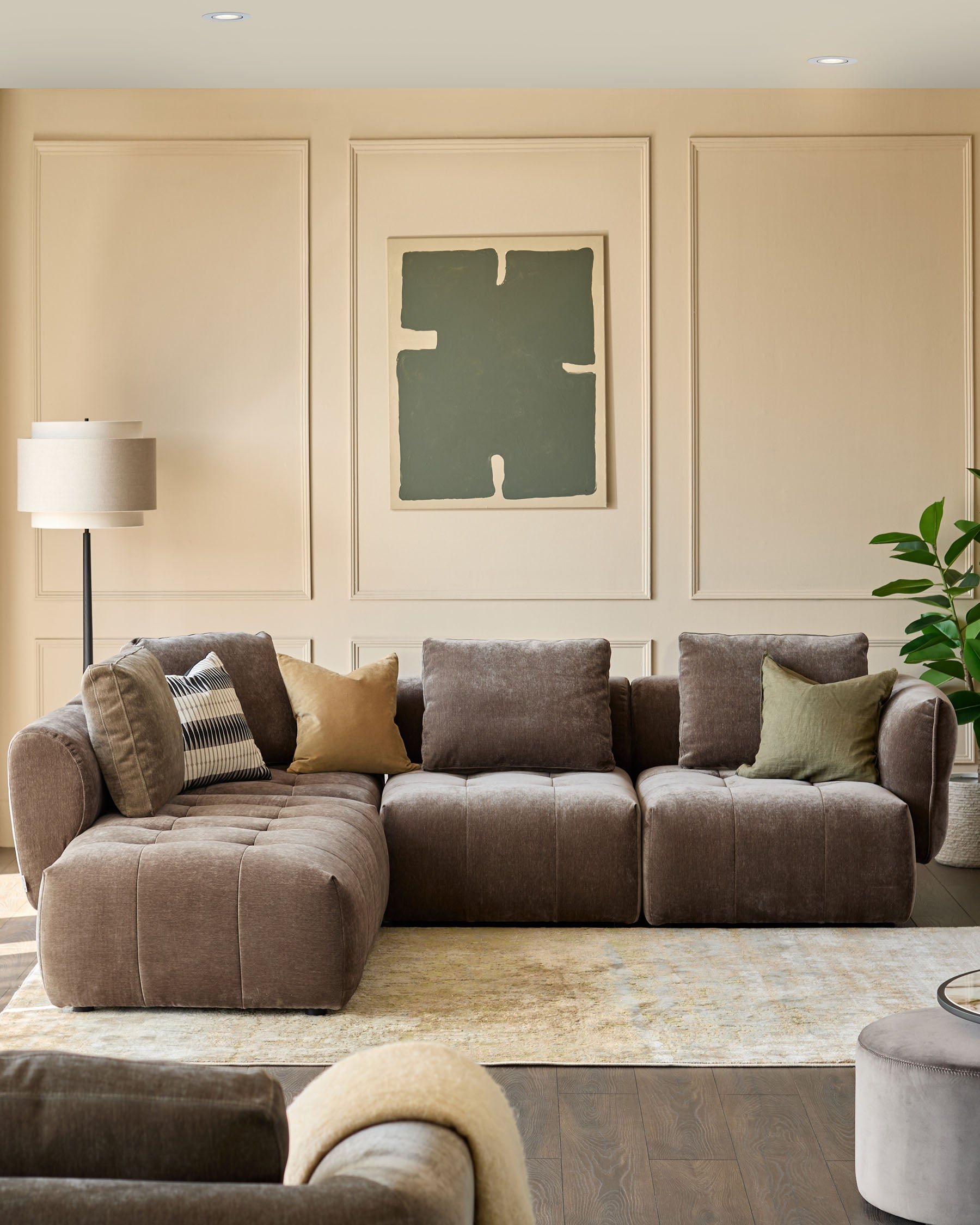 A stylish, modular sofa sits atop a patterned rug, complemented by tasteful cushions and a modern floor lamp.