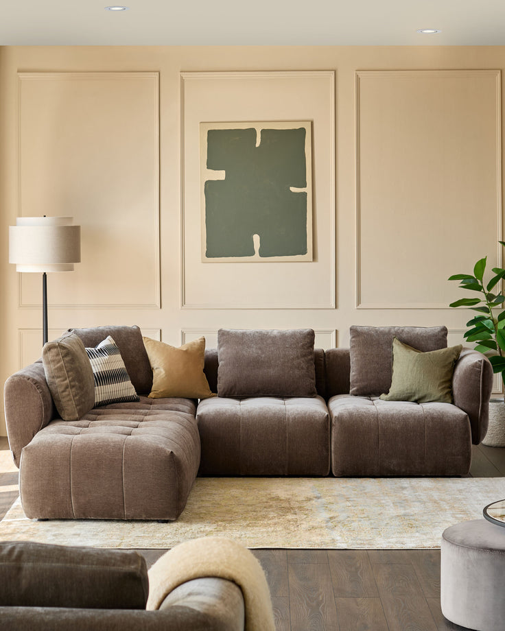 A stylish, modular sofa sits atop a patterned rug, complemented by tasteful cushions and a modern floor lamp.