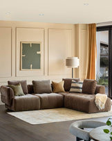 A stylish living room featuring a modular brown sofa adorned with cushions, a patterned rug, and a floor lamp.