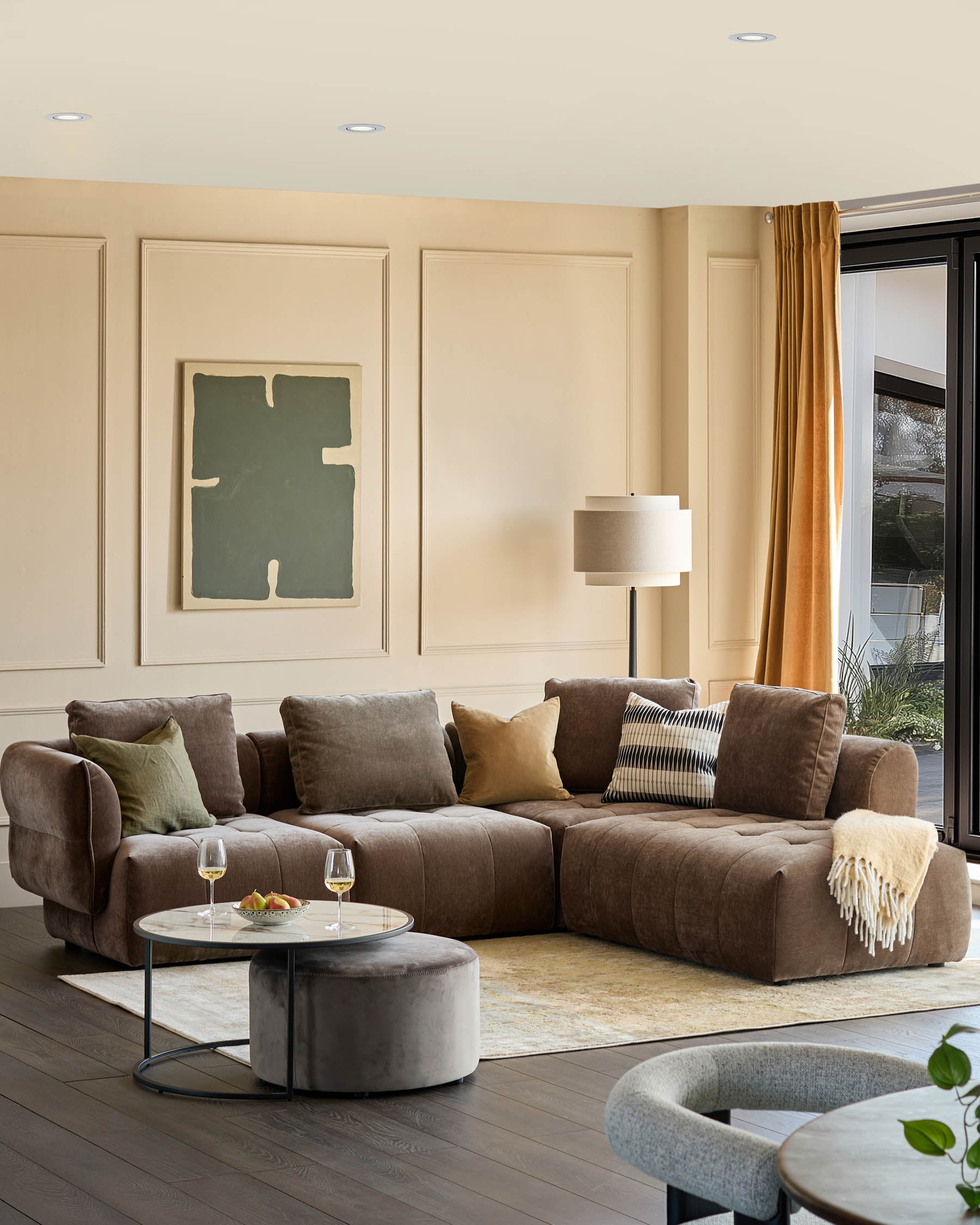 A stylish living room featuring a modular sofa, round coffee table, and a modern accent chair on a dark wooden floor.
