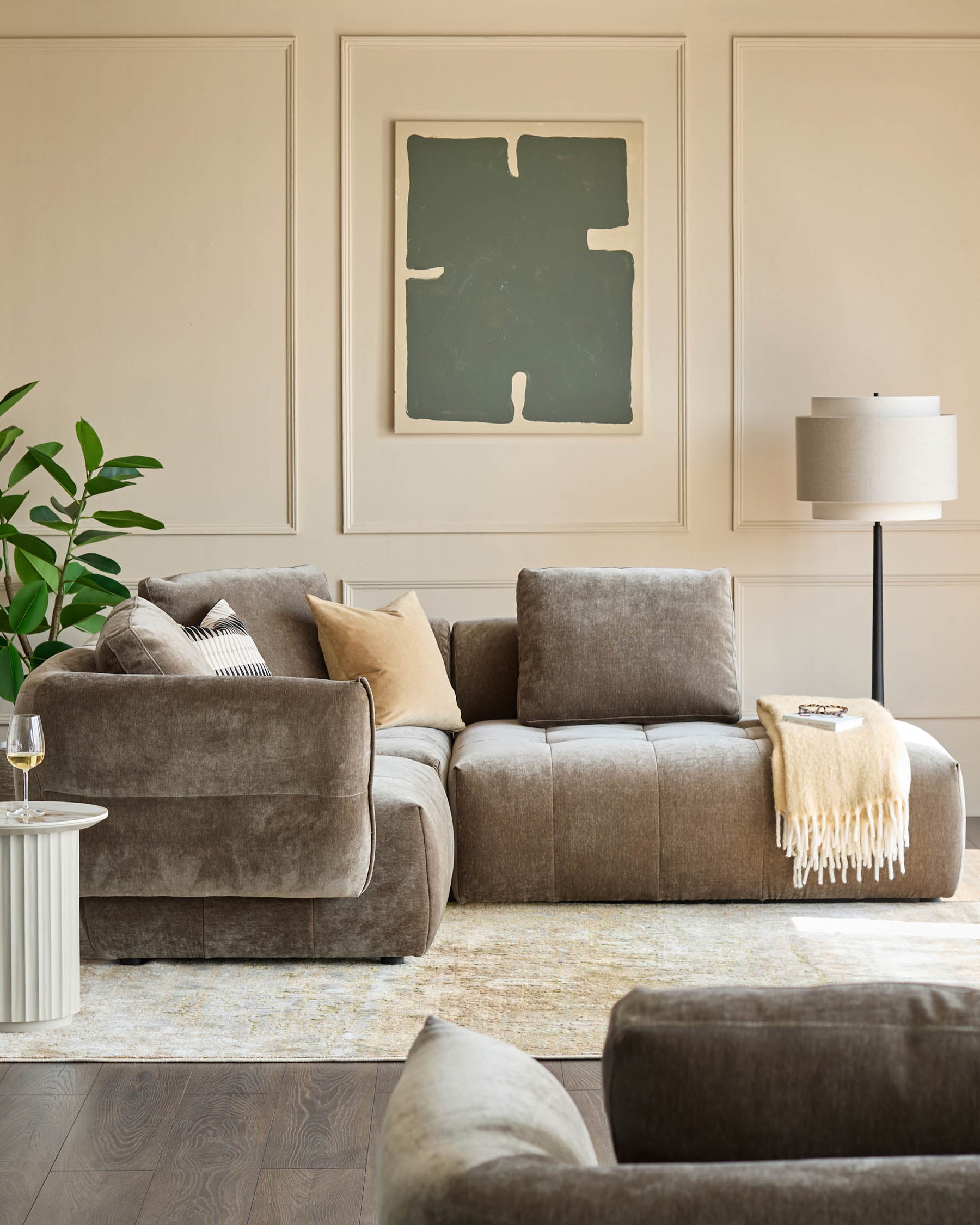 Stylish living room featuring a modular sofa, modern floor lamp, abstract art, and a round side table.