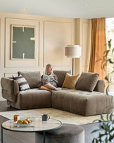 A stylish living room with a large, modular brown sofa, a round coffee table, and a floor lamp.