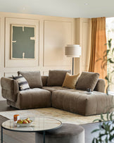 Stylish living room with a large brown sectional sofa, round glass coffee table, and comfy ottoman.