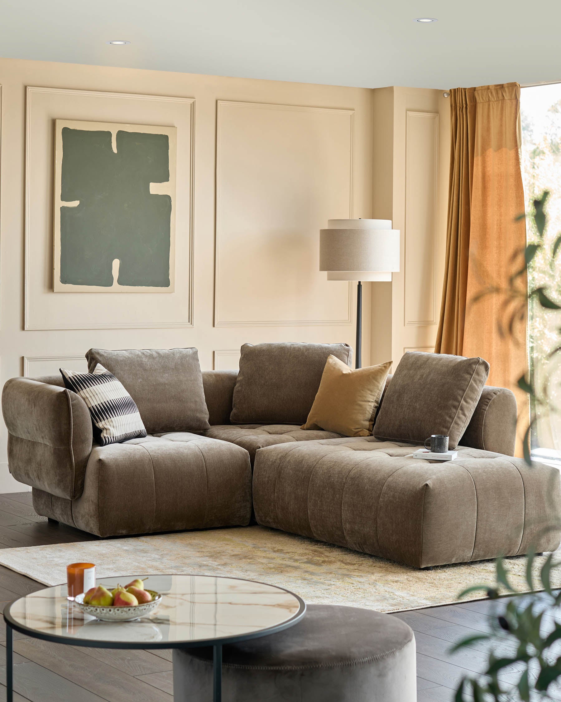Stylish living room with a large brown sectional sofa, round glass coffee table, and comfy ottoman.