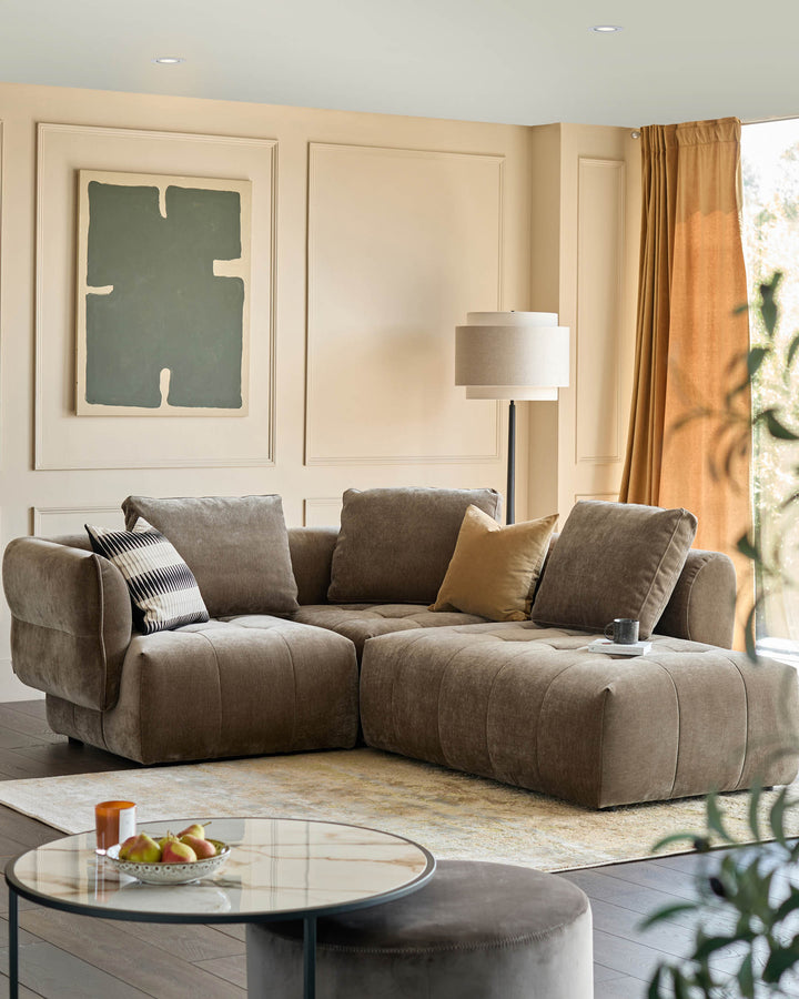 Stylish living room with a large brown sectional sofa, round glass coffee table, and comfy ottoman.