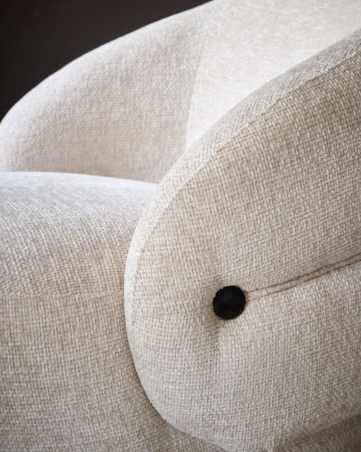 Lillian accent chair in natural fabric, close-up detail of curved armrest with black button accent.
