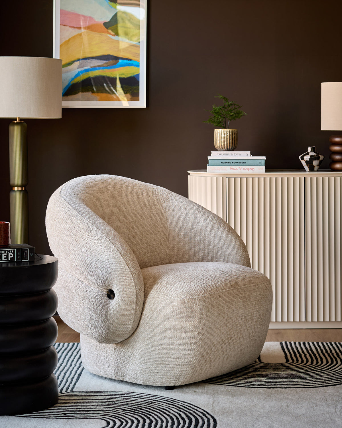 Lillian accent chair in natural fabric with curved, rounded silhouette and black button detail, displayed in modern room setting.