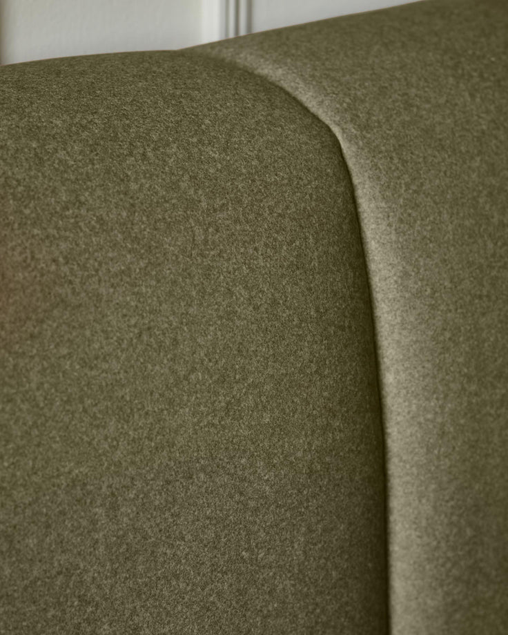 Olive green fabric ottoman bed showing curved headboard detail and soft upholstery texture from side angle.