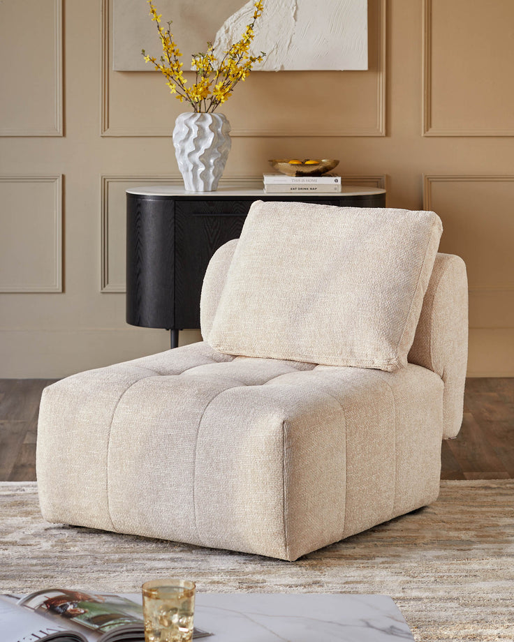 Contemporary beige chair with a cushion seat, complemented by a stylish dark cabinet and flower arrangement.