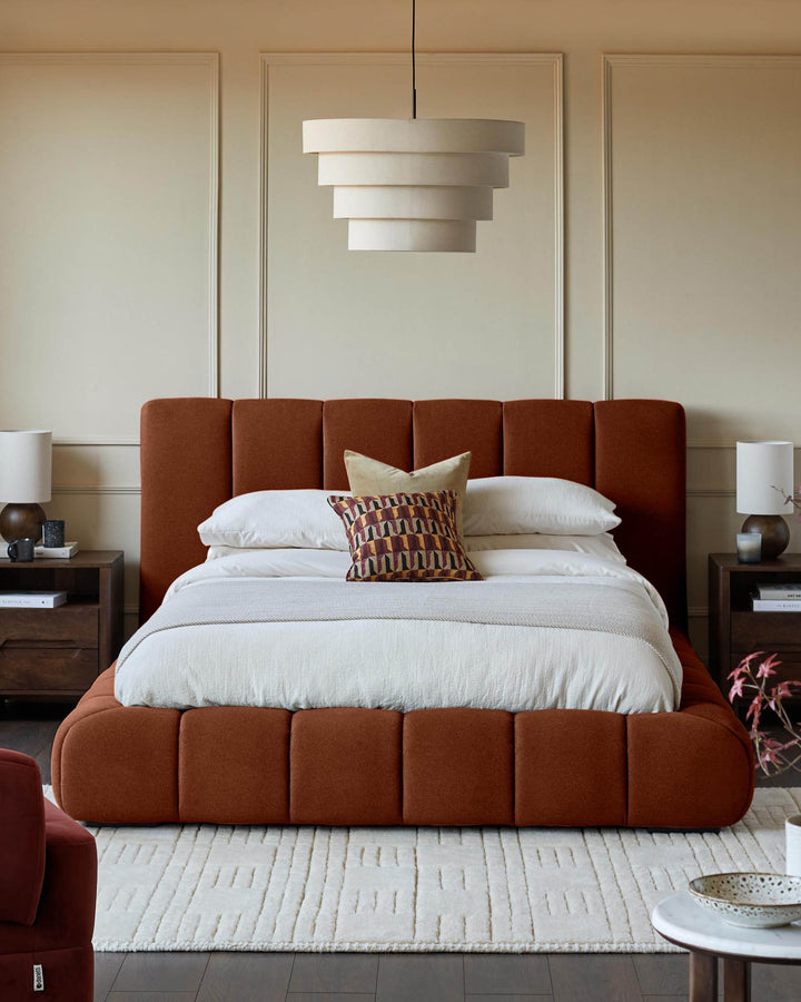 Lillian super king ottoman bed in toffee red fabric, shown in a bedroom setting with white pillows and patterned cushion.