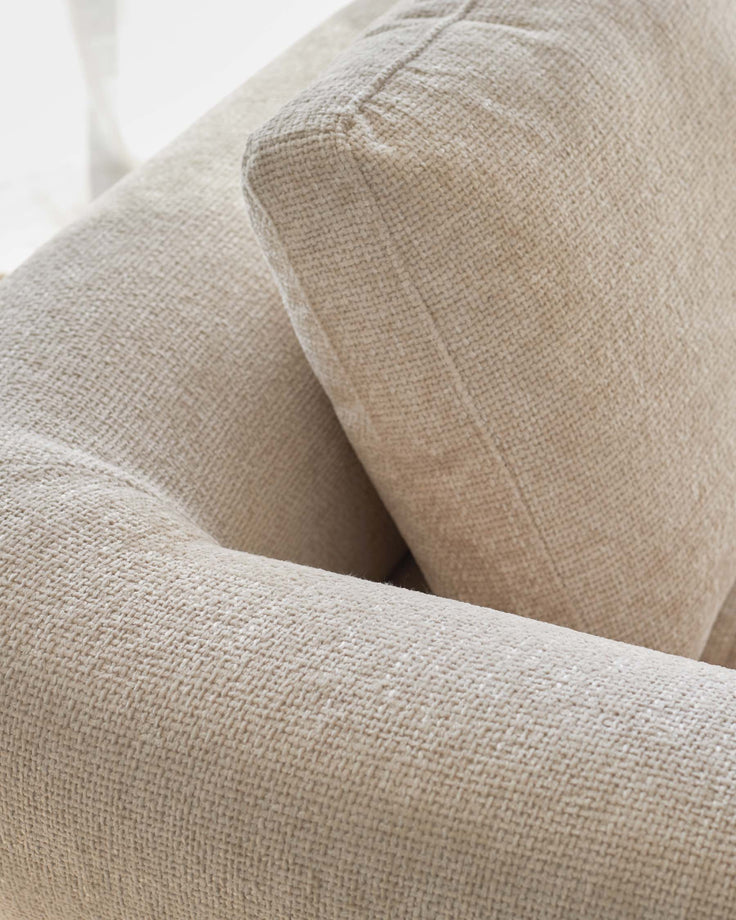 Cream-colored fabric sofa with textured upholstery and soft, rounded arms, perfect for a cozy and inviting living space.