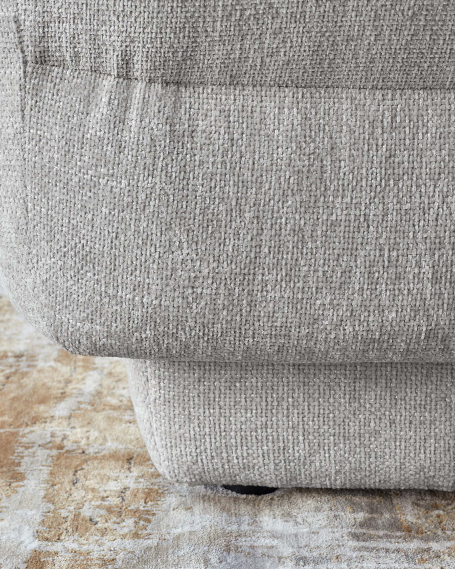 Lillian single module sofa in light grey weave fabric, shown at floor level highlighting the curved base and textured upholstery.
