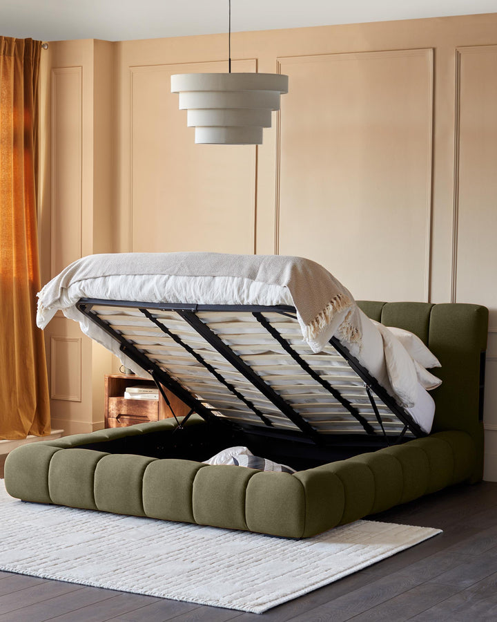 Lillian super king ottoman bed in olive green fabric with storage base open, showing bedding and pillows inside.