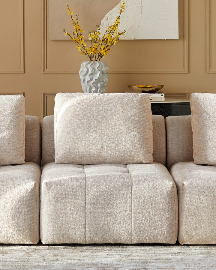 A beige modular sofa with a vase of yellow flowers displayed on top of it. Comfortable and stylish living room furniture.