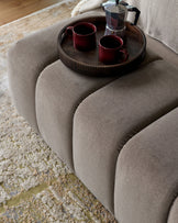 Lillian bench in mocha fabric with curved, rounded edges, styled with a dark tray holding two burgundy mugs and a moka pot.
