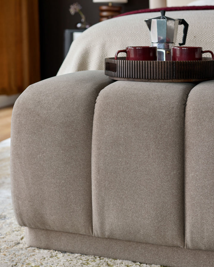 Lillian bench in mocha fabric with rounded, channeled sections and metal tray top, styled in a modern living room.
