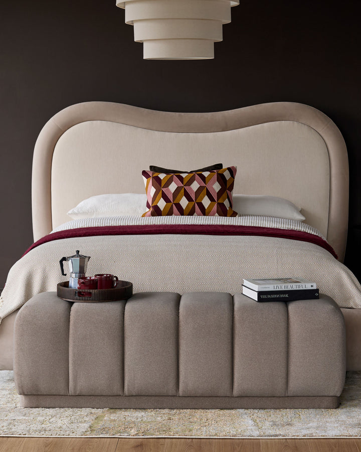 Lillian bench in mocha fabric with vertical channel quilting, shown at foot of bed in styled bedroom setting.