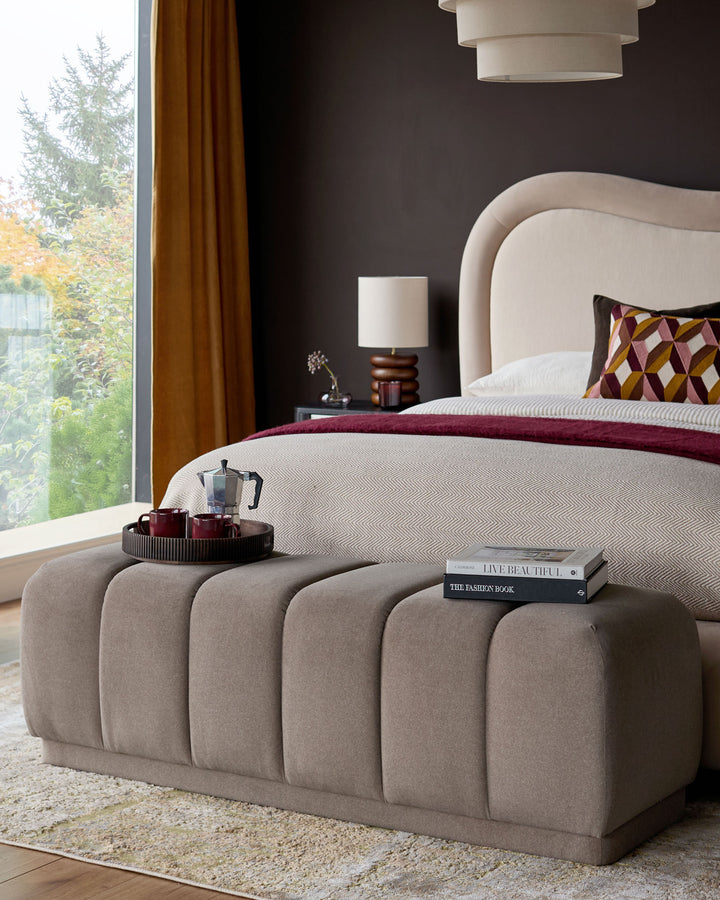 Mocha upholstered bench with vertical channel quilting at foot of bed in modern bedroom setting.