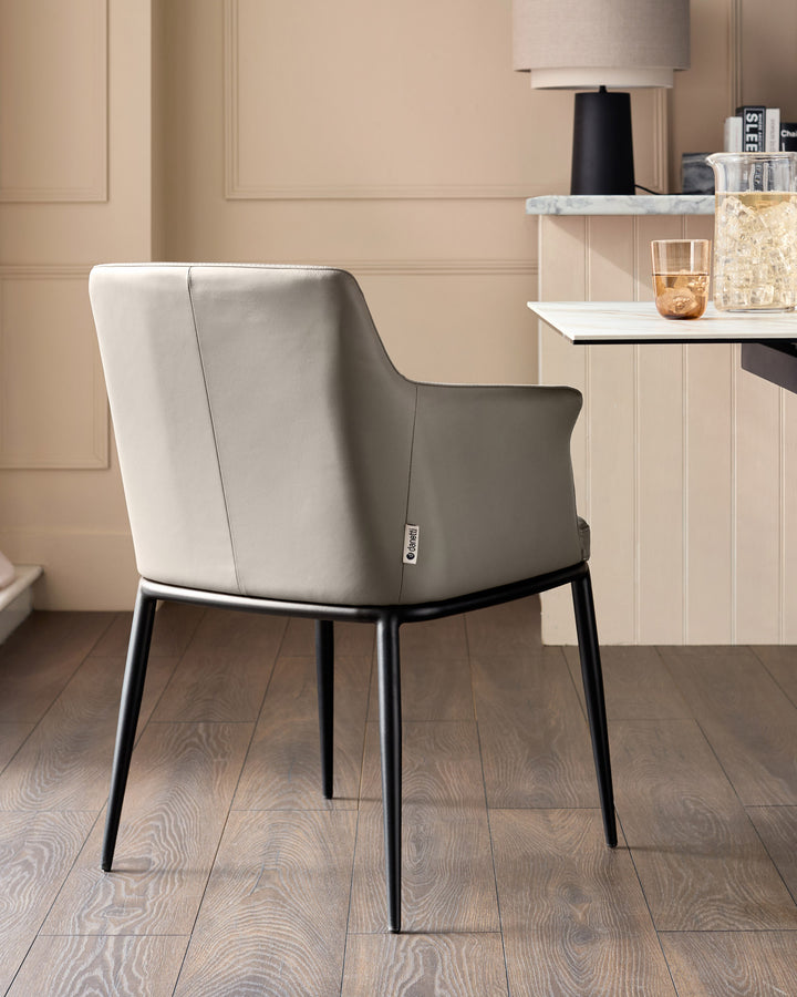 Logan dining chair in light grey leather with black metal legs, shown from rear angle in a modern interior setting.