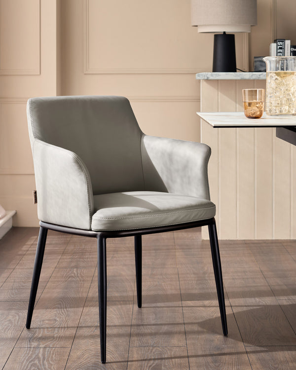 Light grey leather dining chair with black metal legs, shown in a modern dining room setting with marble-top table.