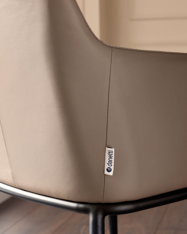 Logan dining chair in mocha leather, showing close-up of seam detail and brand label on backrest.