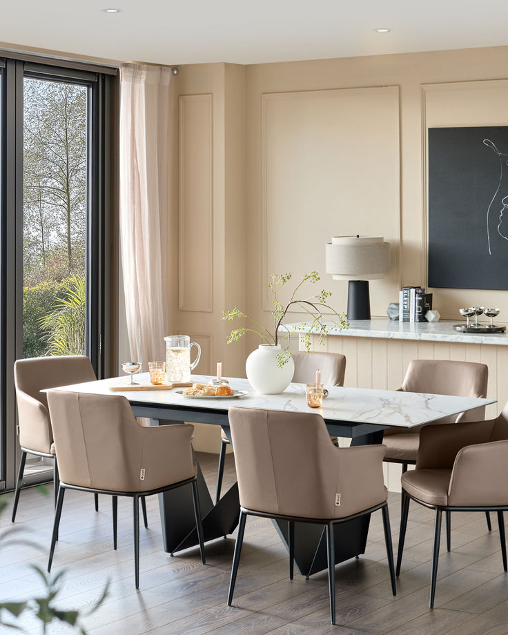 Logan dining chair in mocha leather, shown in a modern dining room setting with black metal legs and curved back design.
