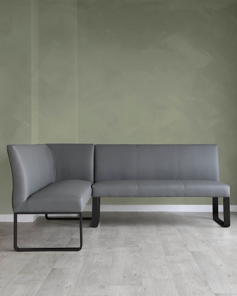 Modern minimalist L-shaped sectional sofa with a sleek design, featuring grey upholstery and a sturdy black metal frame with straight lines, set against a green wall and light wooden flooring.