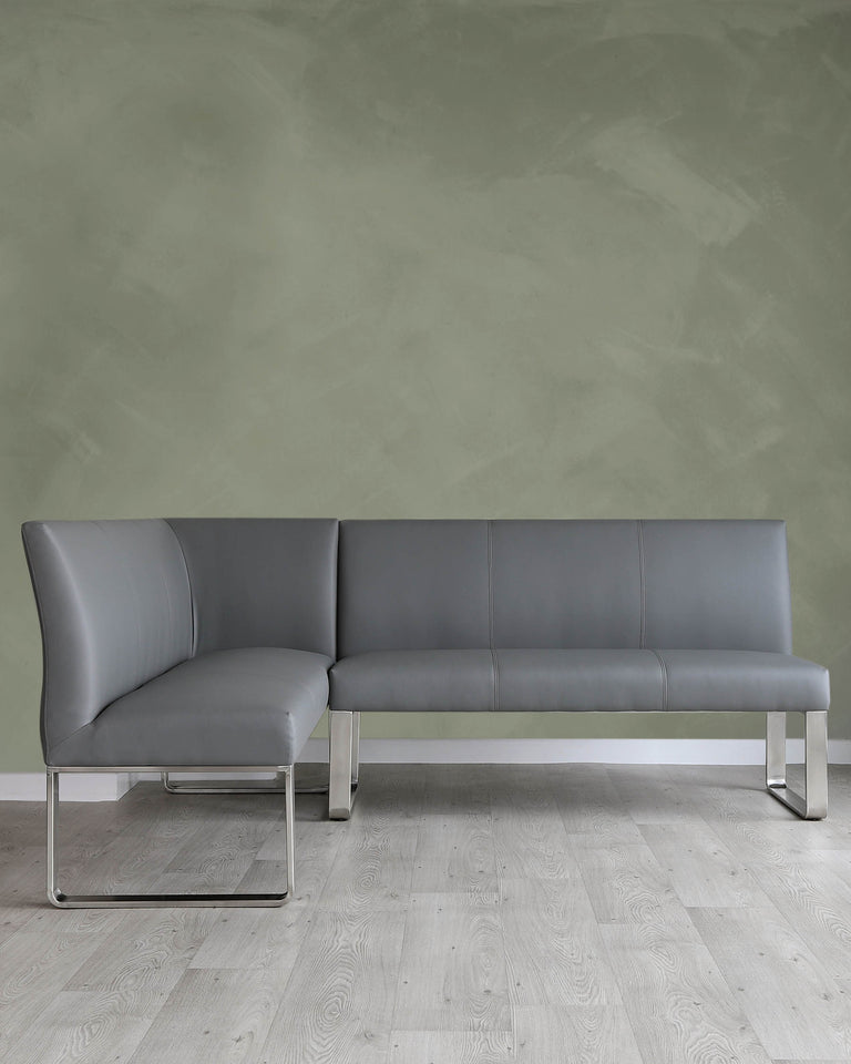 Modern minimalist sectional sofa with a sleek metallic frame and grey upholstery against a muted green wall, placed on a light wooden floor.