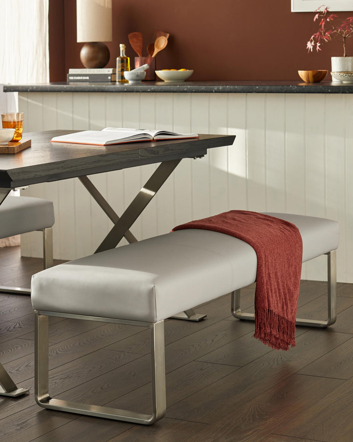 Contemporary dining scene: a sleek grey bench seat with metal legs and a dark wood table. Stylish and modern.
