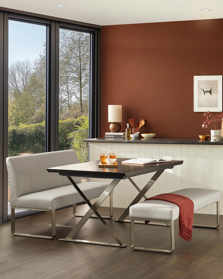 A dining area with a table, backless bench, and a bench seat. The furnishings are grey with metallic legs.