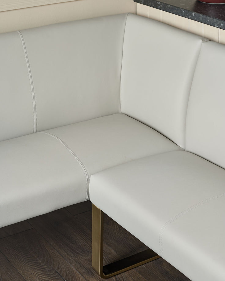 Light grey faux leather corner dining bench with brushed brass leg, showing seat and backrest detail.