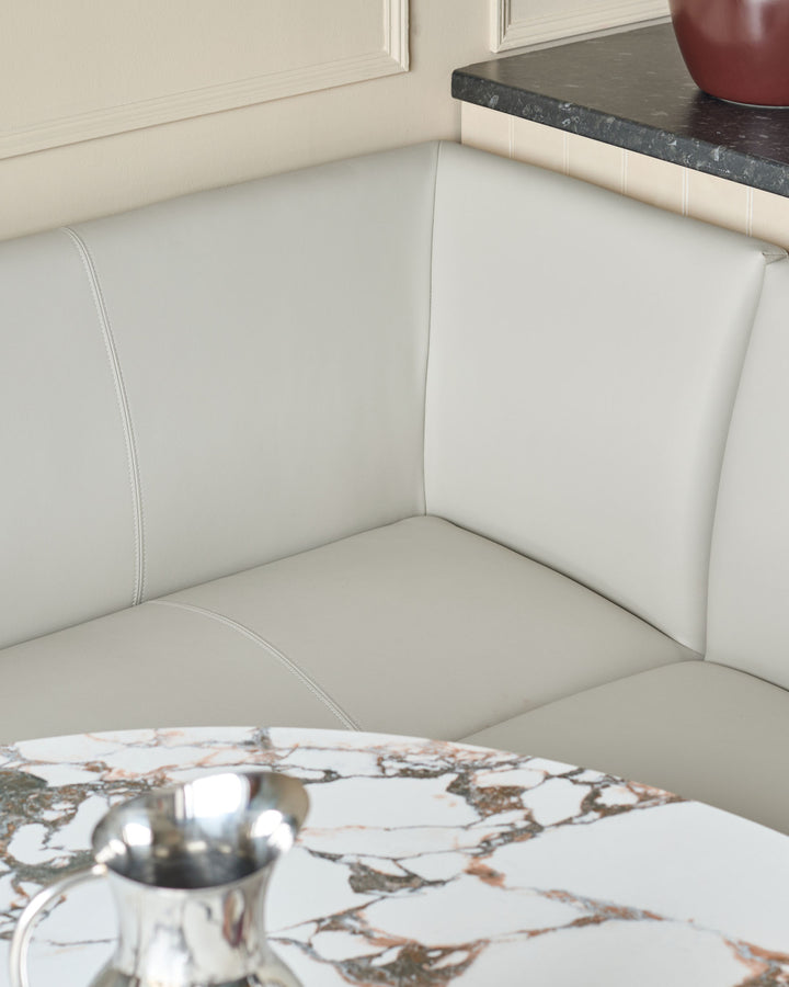 Light grey faux leather left-hand corner dining bench with brushed brass legs, shown in a styled interior setting.