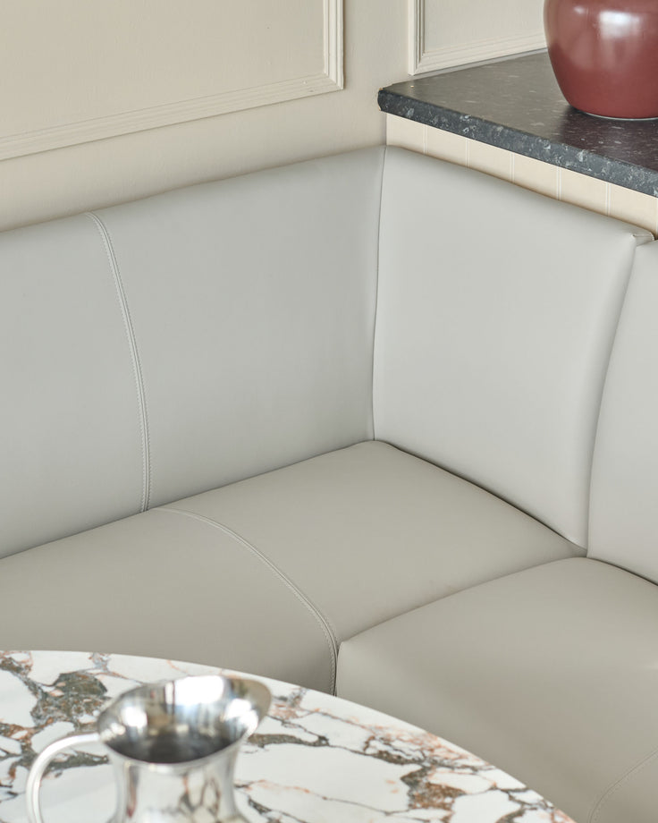 Light grey faux leather corner dining bench with chrome legs, showing the padded seat and backrest detail.