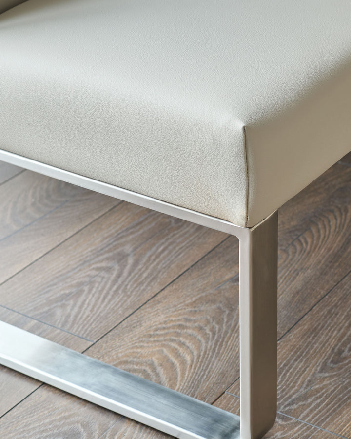 Light grey faux-leather corner bench with stainless steel frame, shown at angle on wooden floor.