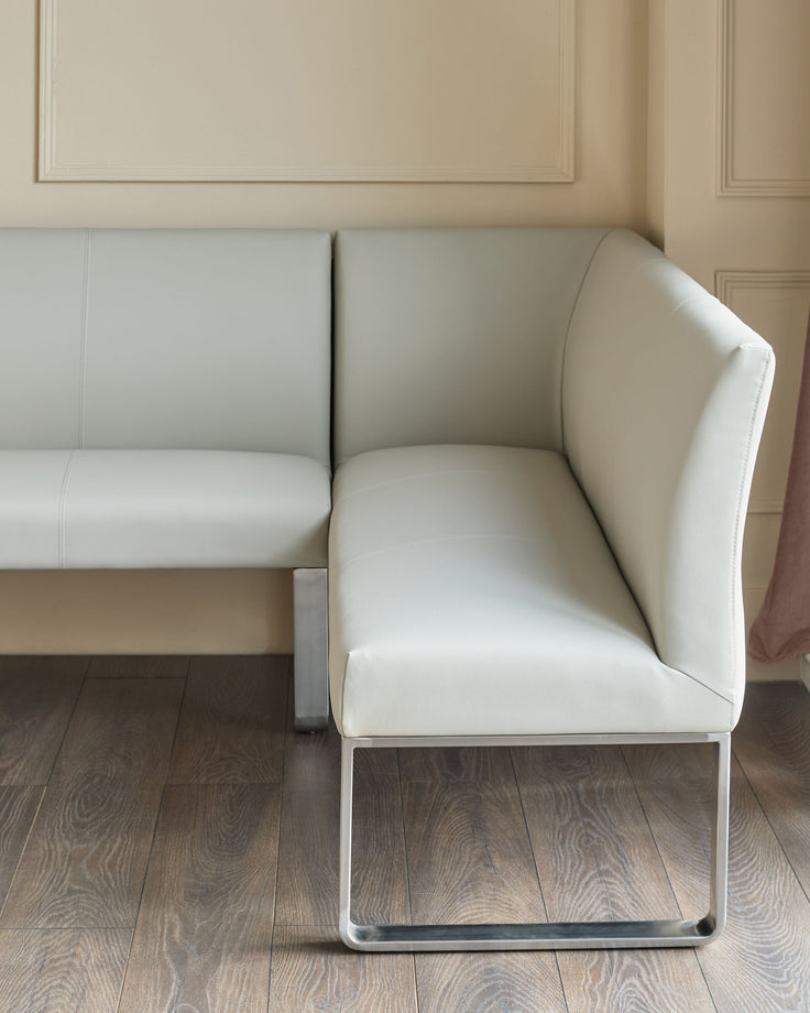 Light grey faux-leather corner bench with stainless steel frame, showing angled view of seat and backrest detail.