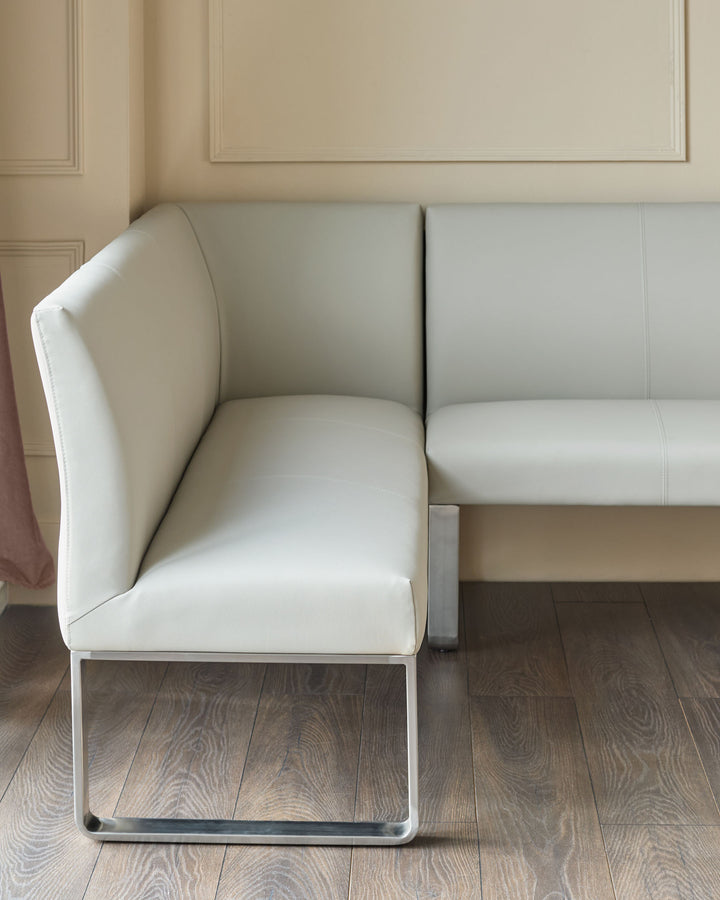 Light grey faux-leather corner bench with stainless steel base, shown from side angle in modern interior.
