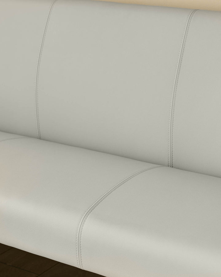 Light grey upholstered corner bench with curved seating, stitched seams, and black legs, shown from close-up angle.