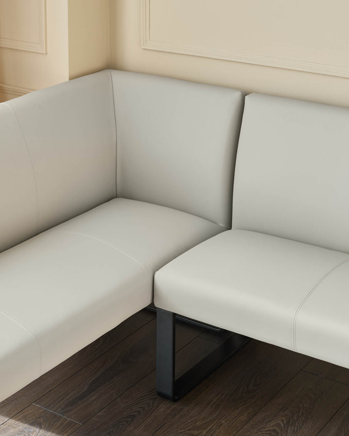 Light grey upholstered corner bench with black metal legs, shown from a side angle in a neutral room setting.