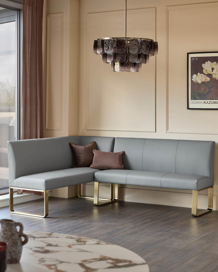 Loop 5-seater corner dining bench in mid-grey faux leather with brushed brass legs, shown in a modern living room setting.