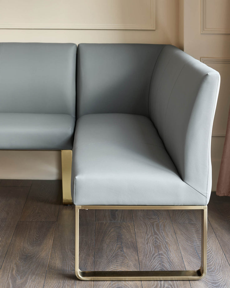 Grey faux leather corner dining bench with brushed brass legs, shown from side angle in modern interior setting.