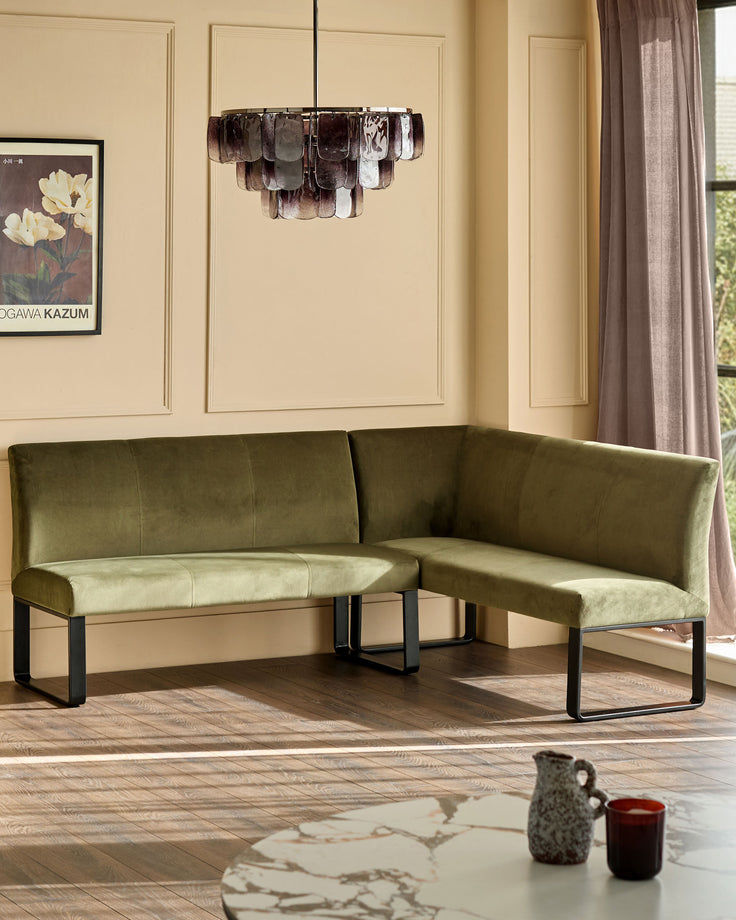 Olive green velvet corner bench with black metal legs, shown in modern living room setting.