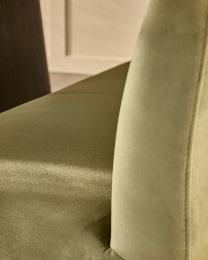 Olive-green velvet bench with backrest, close-up detail showing curved backrest and seat upholstery.
